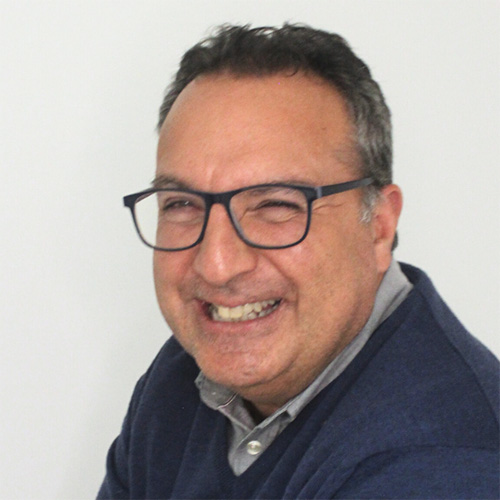 Hombre sonriendo con gafas y suéter azul oscuro