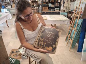 Karina Cappato sosteniendo un libro sobre pintura y restauración en su estudio
