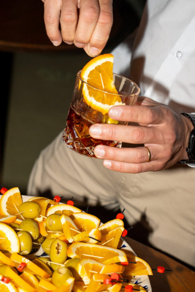 Preparaci&oacute;n de c&oacute;cteles con rodajas de naranja y aceitunas en un evento