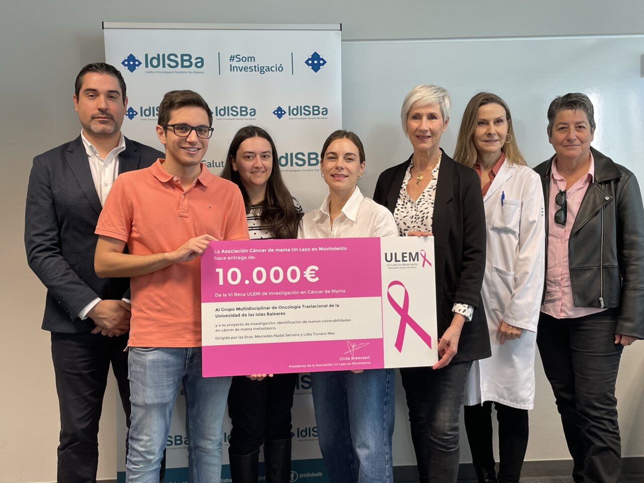Grupo de personas sosteniendo un cheque para la investigación del cáncer de mama.
