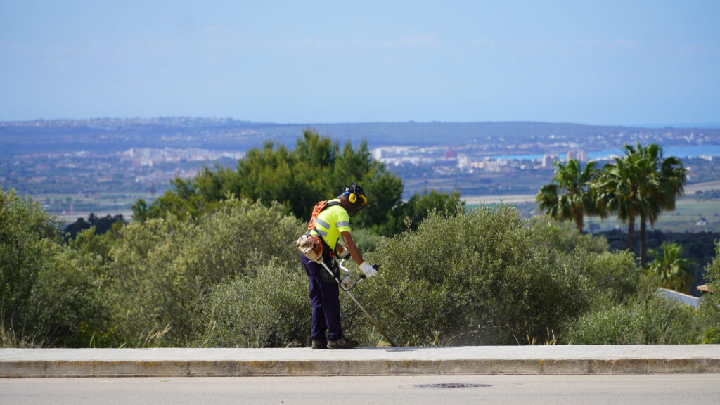 Trabajador desbrozando vegetación en Marratxí con paisaje de fondo
