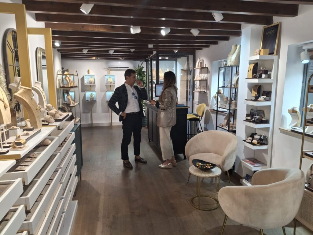 Luca Lorenzini conversando con una clienta en su tienda de joyería.