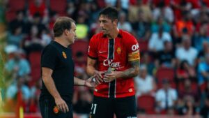 Entrenador y jugador del RCD Mallorca conversando en el campo.
