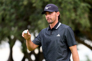 Marco Penge sosteniendo una bola de golf en el campo.