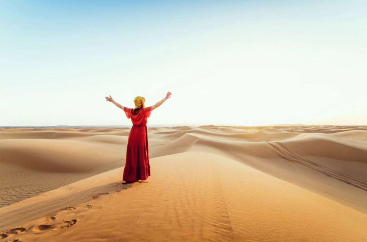 Mujer en vestido rojo disfrutando del desierto de Marruecos