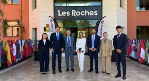 Grupo de personas frente a la escuela Les Roches con banderas de varios países.