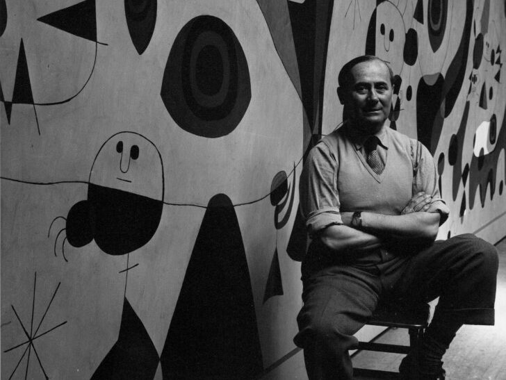 Joan Miró posando frente a una obra mural colorida