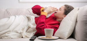 Persona con resfriado usando un pañuelo en el sofá