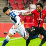 Jugadores de RCD Mallorca y Levante en un partido de fútbol bajo la lluvia