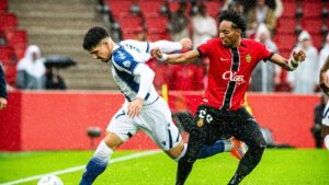 Jugadores de RCD Mallorca y Levante en un partido de fútbol bajo la lluvia