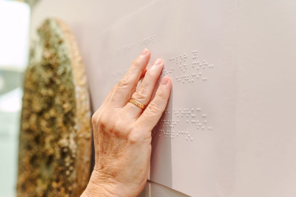 Mano tocando una obra de arte con texto en braille