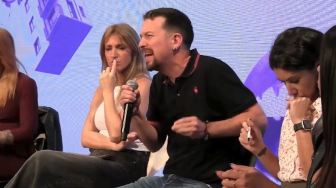 Pablo Iglesias hablando en un evento pol&iacute;tico con otros participantes.