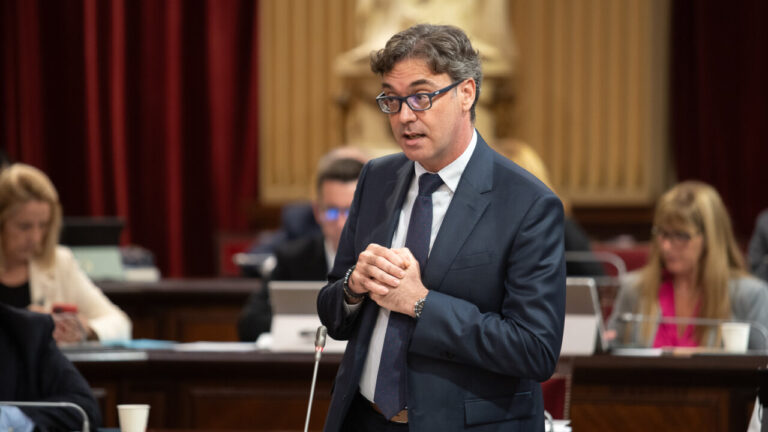 Hombre hablando en el parlamento con otros asistentes al fondo