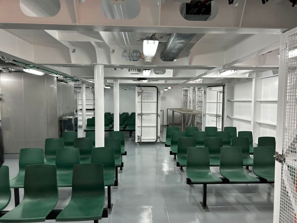 Interior de la sala de recepci&oacute;n del buque Duque de Ahumada con asientos verdes.