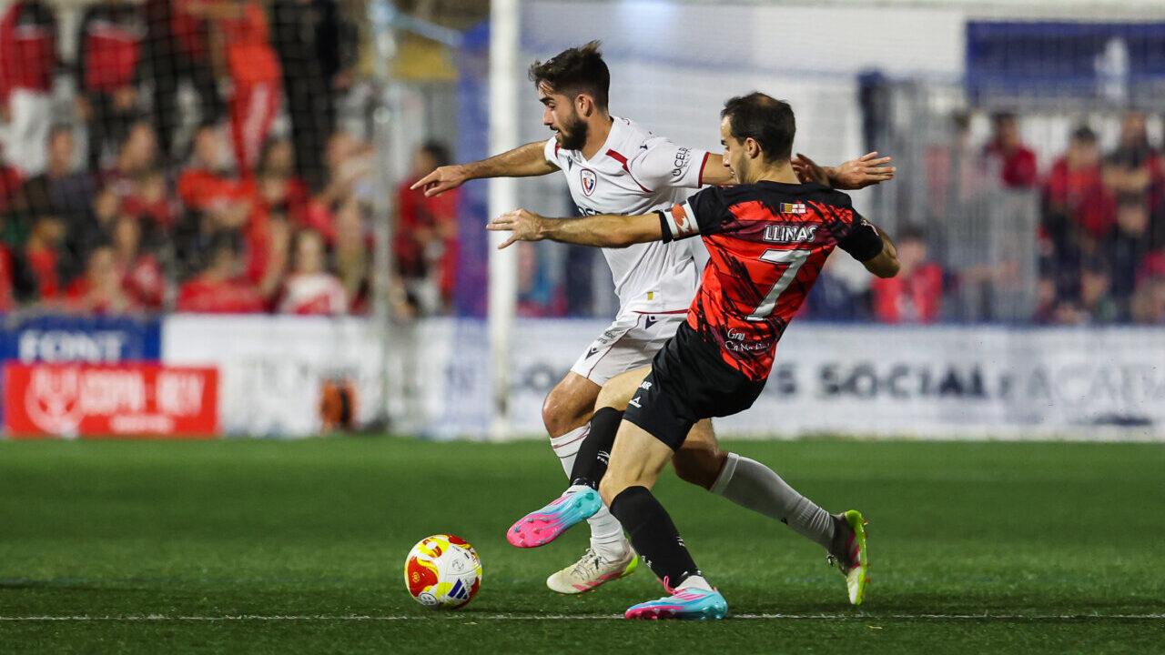 Jugadores de Sant Jordi y Osasuna compiten por el bal&oacute;n en un partido de f&uacute;tbol.