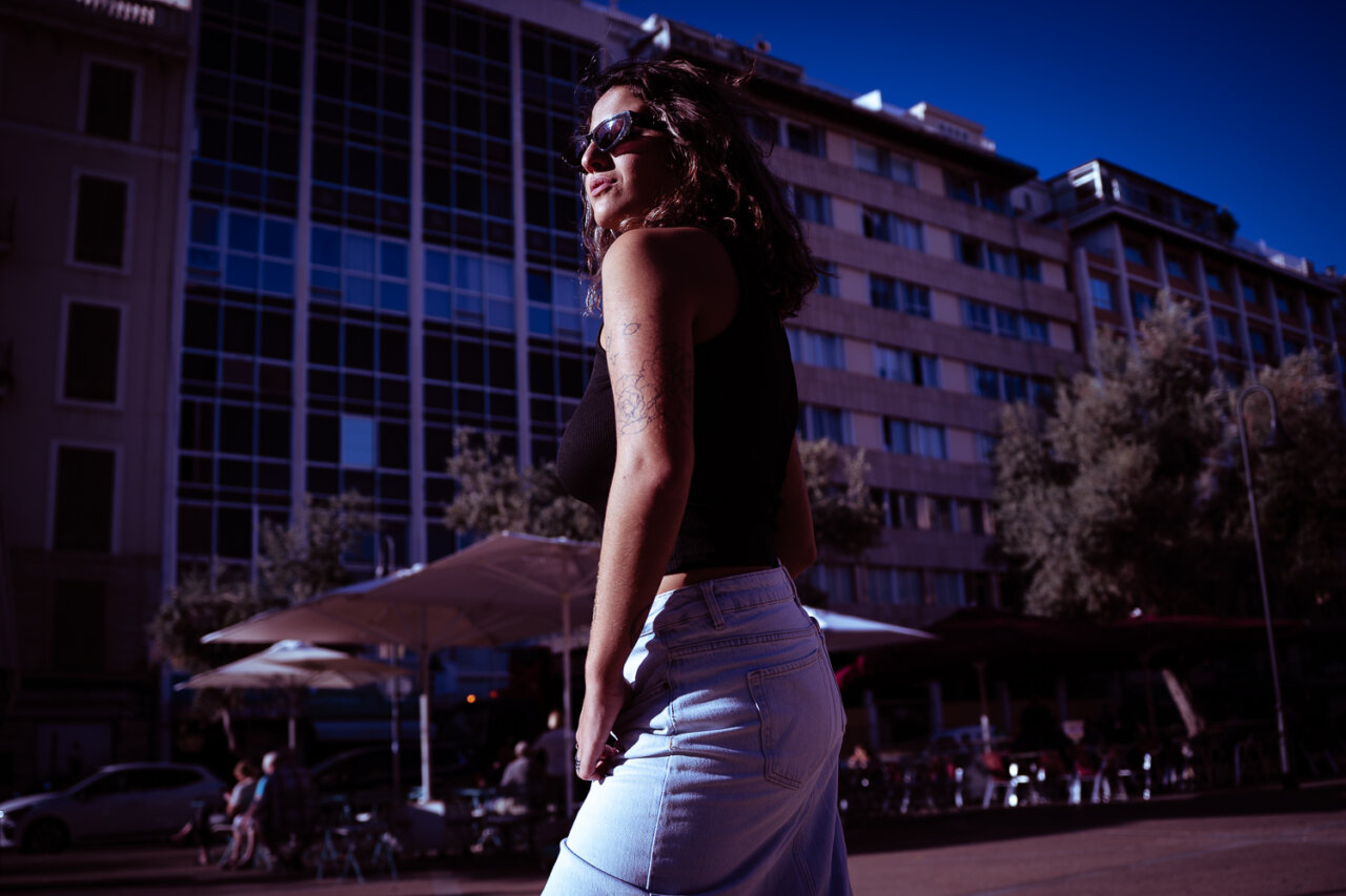 Mujer con cabello rizado y gafas de sol en una plaza urbana