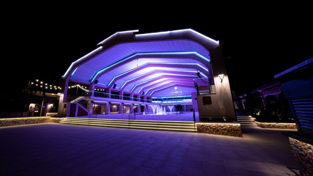 Vista nocturna del auditorio Son Amar iluminado en colores vibrantes.