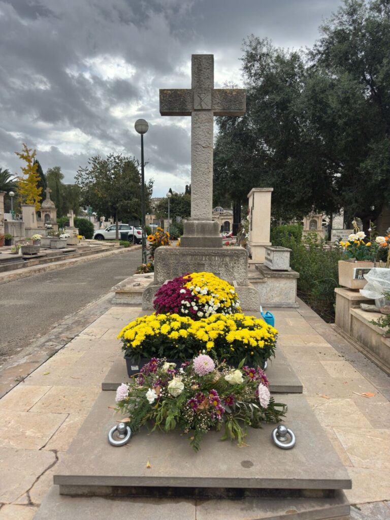 Tumba en el cementerio de Palma adornada con flores coloridas.