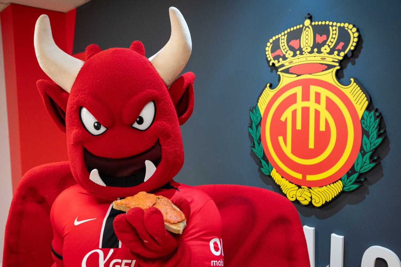 Mascota del RCD Mallorca sosteniendo un bocadillo de sobrasada