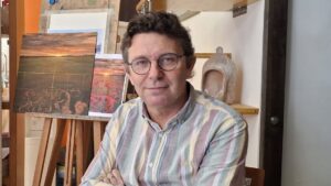 David Santos posando en su estudio de pintura con obras de fondo