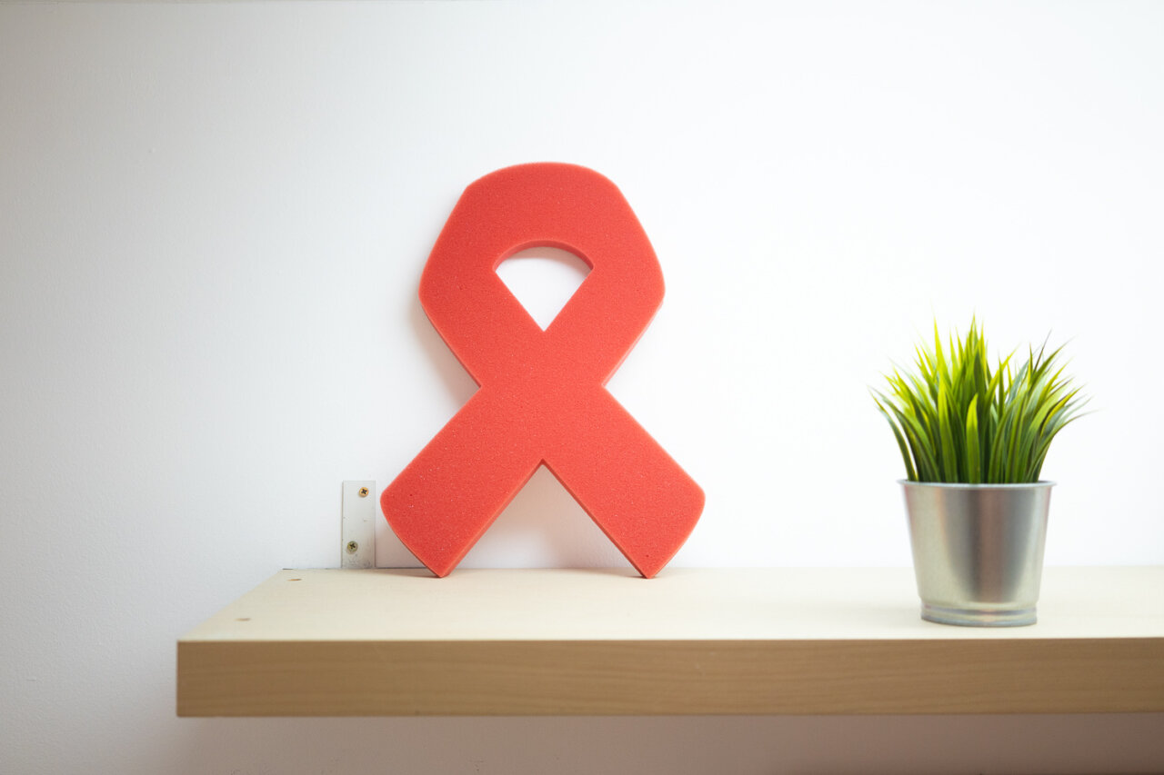 Ribón rojo de concienciación sobre el SIDA en una estantería