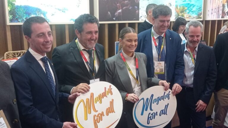 Representantes en la World Travel Market sosteniendo carteles de Magaluf