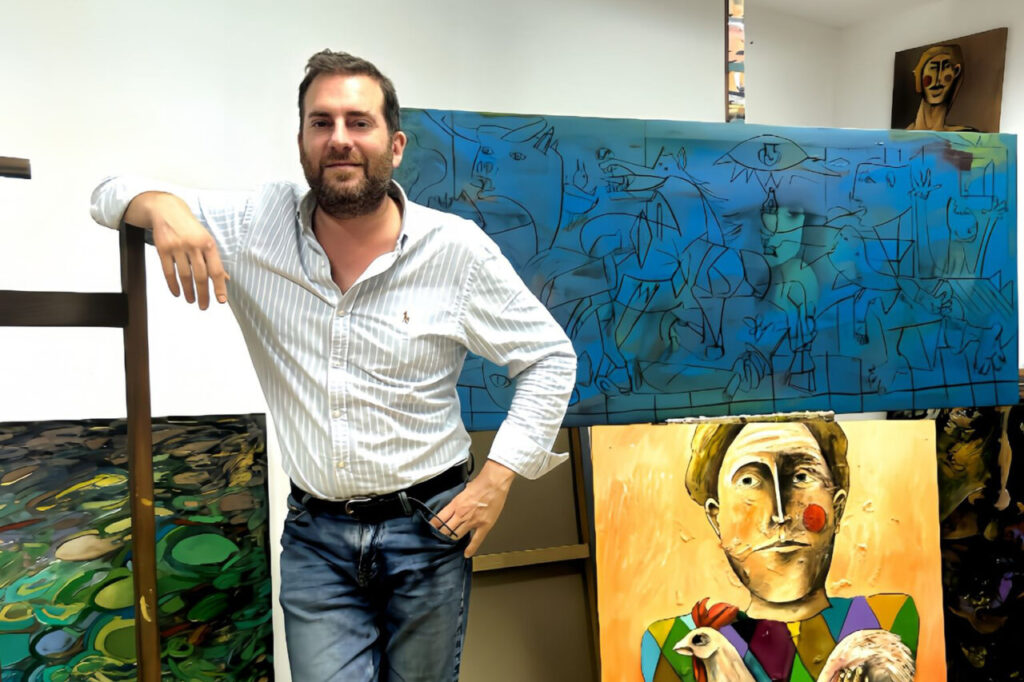 Martín Garrido posando en su estudio con obras de arte