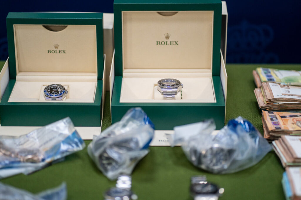 Dos relojes Rolex en cajas junto a billetes en una mesa