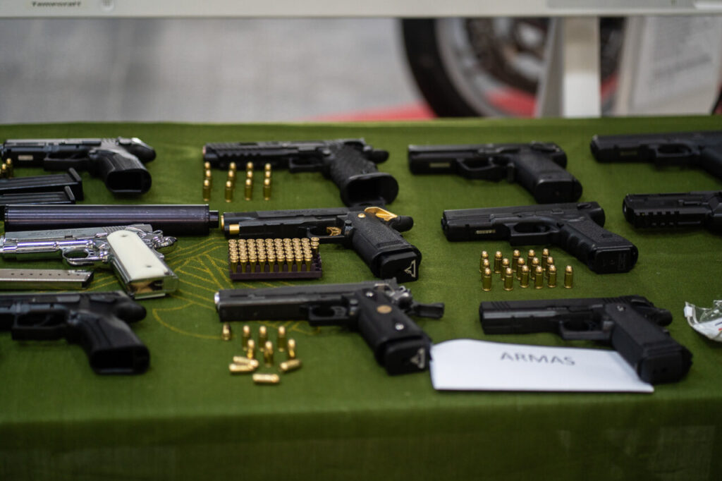 Diversas armas de fuego y municiones sobre una mesa verde