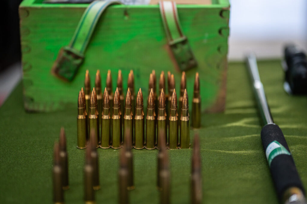 Cartuchos de munici&oacute;n dispuestos en una mesa verde.