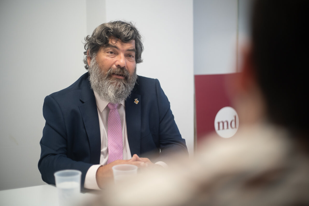 Hombre con barba y traje hablando en una reunión