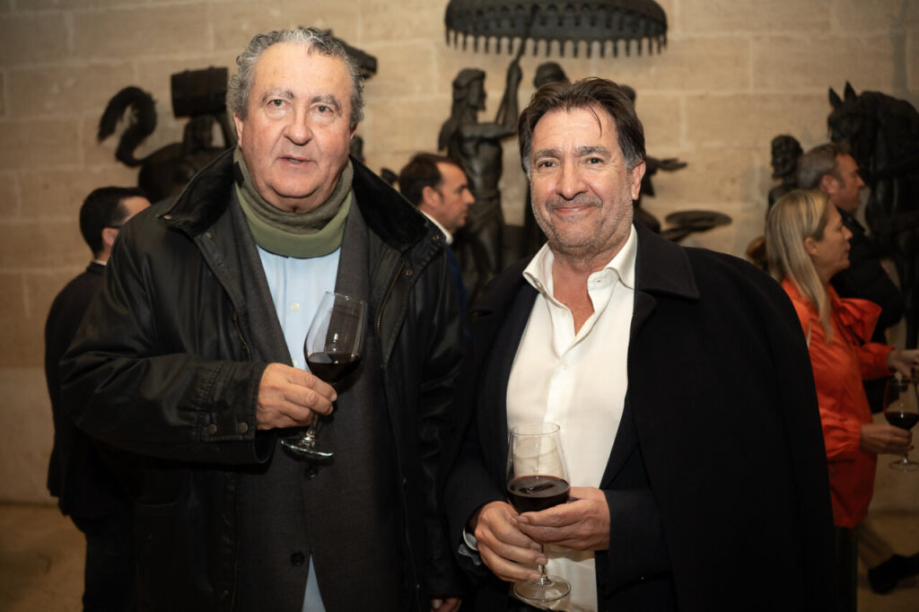 Dos hombres sosteniendo copas de vino en un evento social.