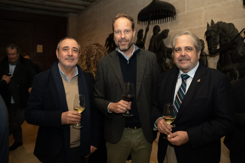 Tres hombres sosteniendo copas en un evento social