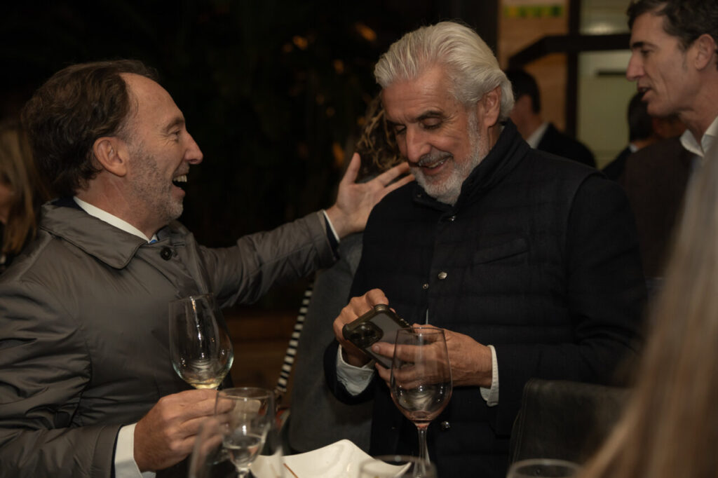 Dos hombres conversando y sonriendo en un evento social.