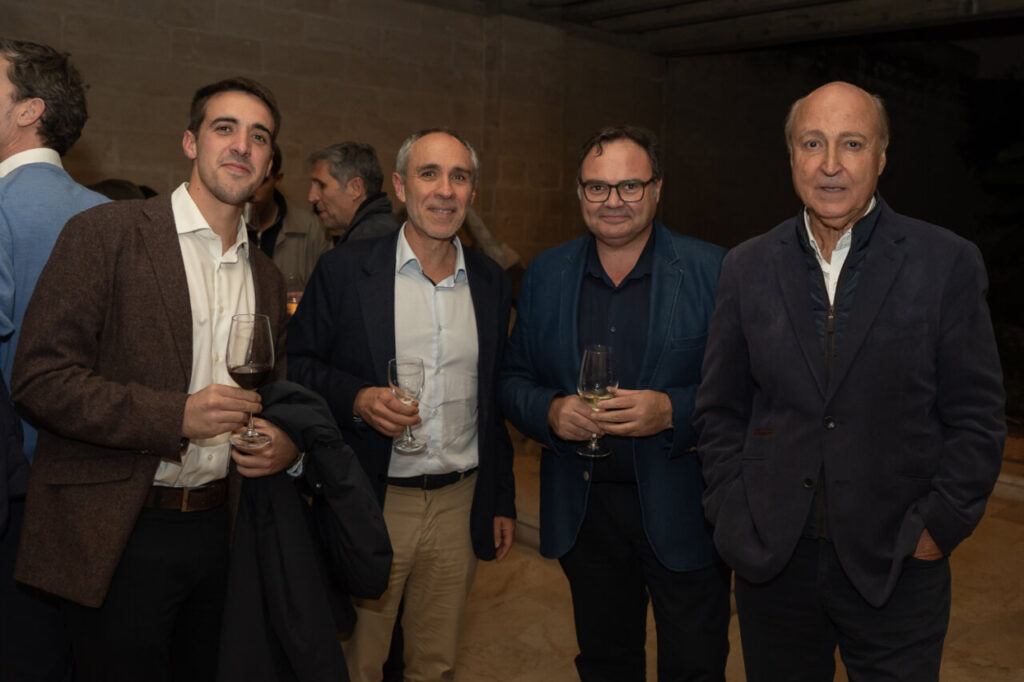 Cuatro hombres sosteniendo copas en un evento social.