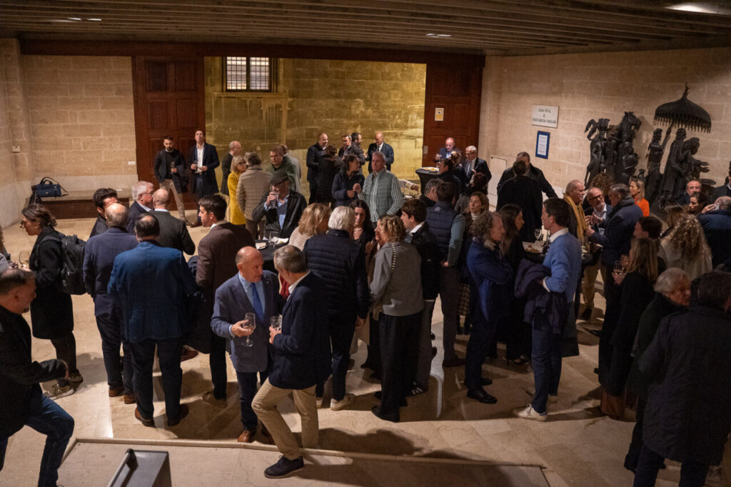 Evento social con muchas personas conversando y disfrutando bebidas.