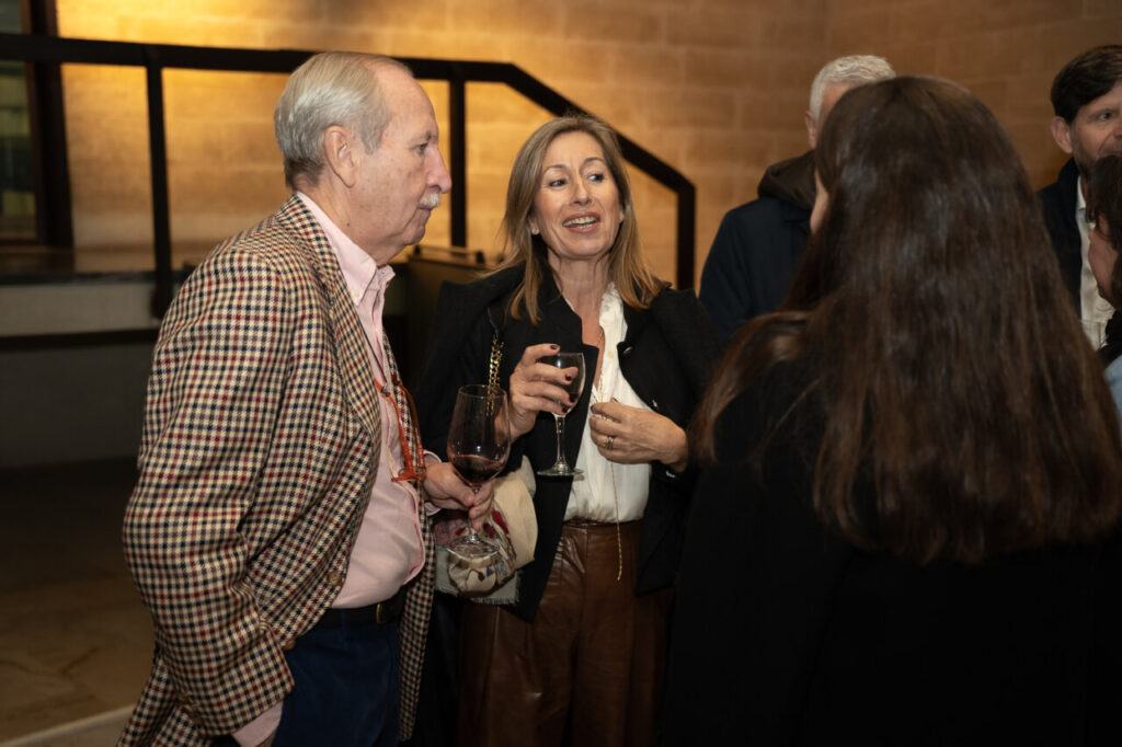 Personas conversando en un evento con copas de vino
