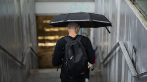 Persona con paraguas negro bajando escaleras en un día lluvioso