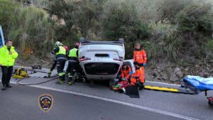 Intervención de bomberos en un accidente de coche volcado en carretera