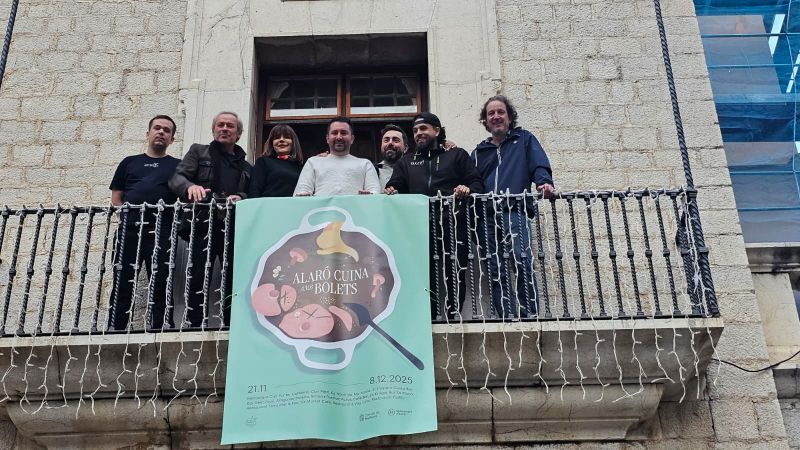Grupo de personas en un balcón con cartel de Alaró cuina amb bolets