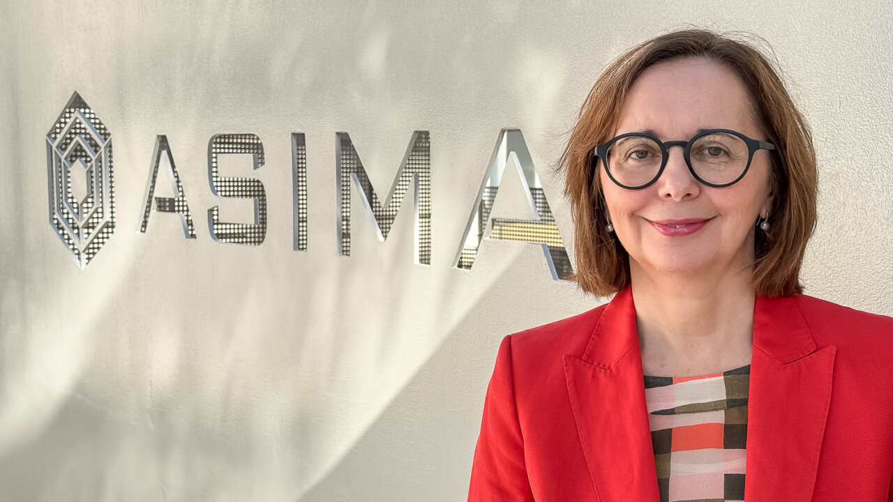 Ana Reguera posando frente al logo de Asima