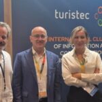 Tres personas en un stand de tecnología turística en Baleares