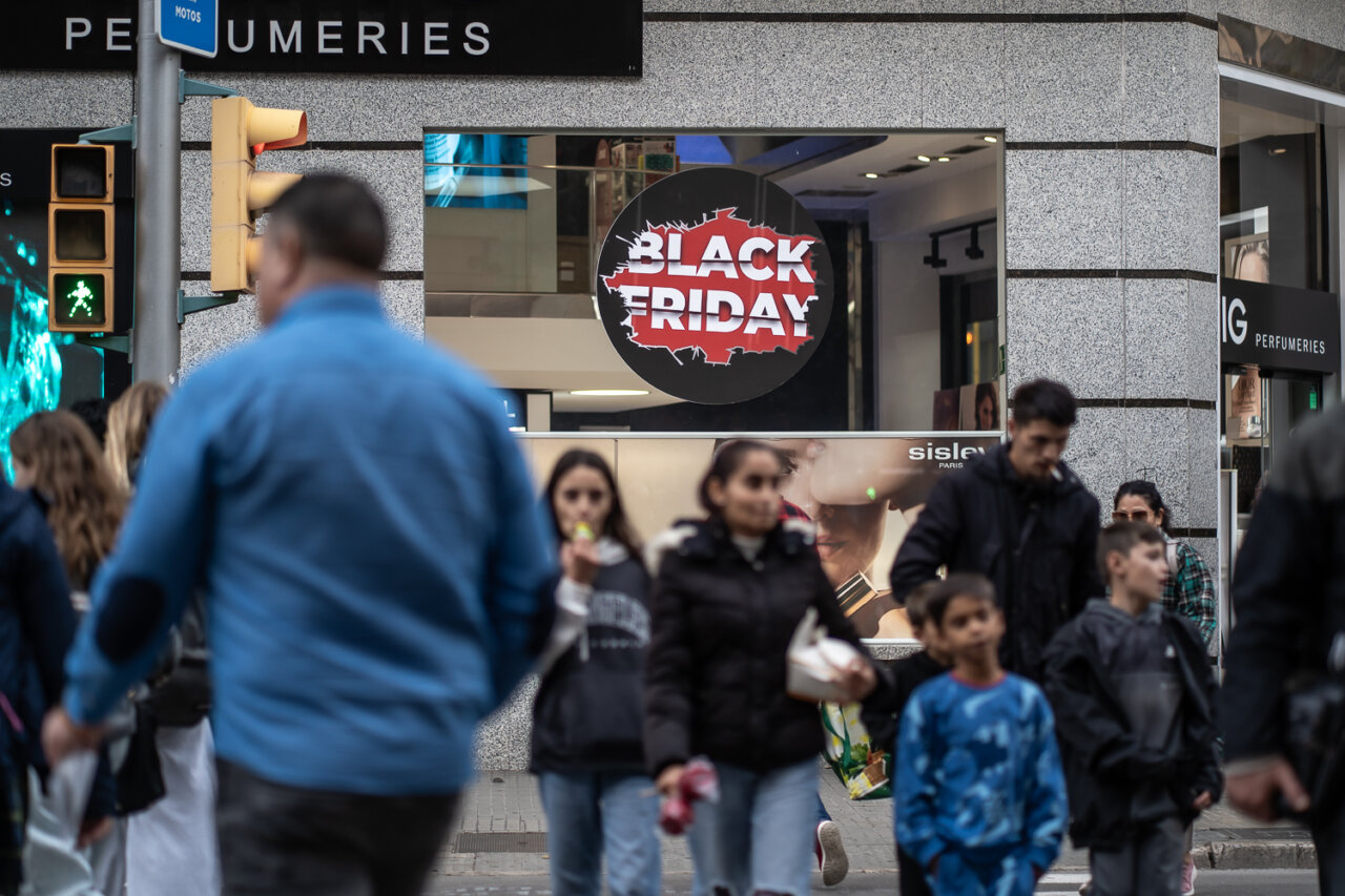 Multitud de personas caminando frente a un anuncio de Black Friday.