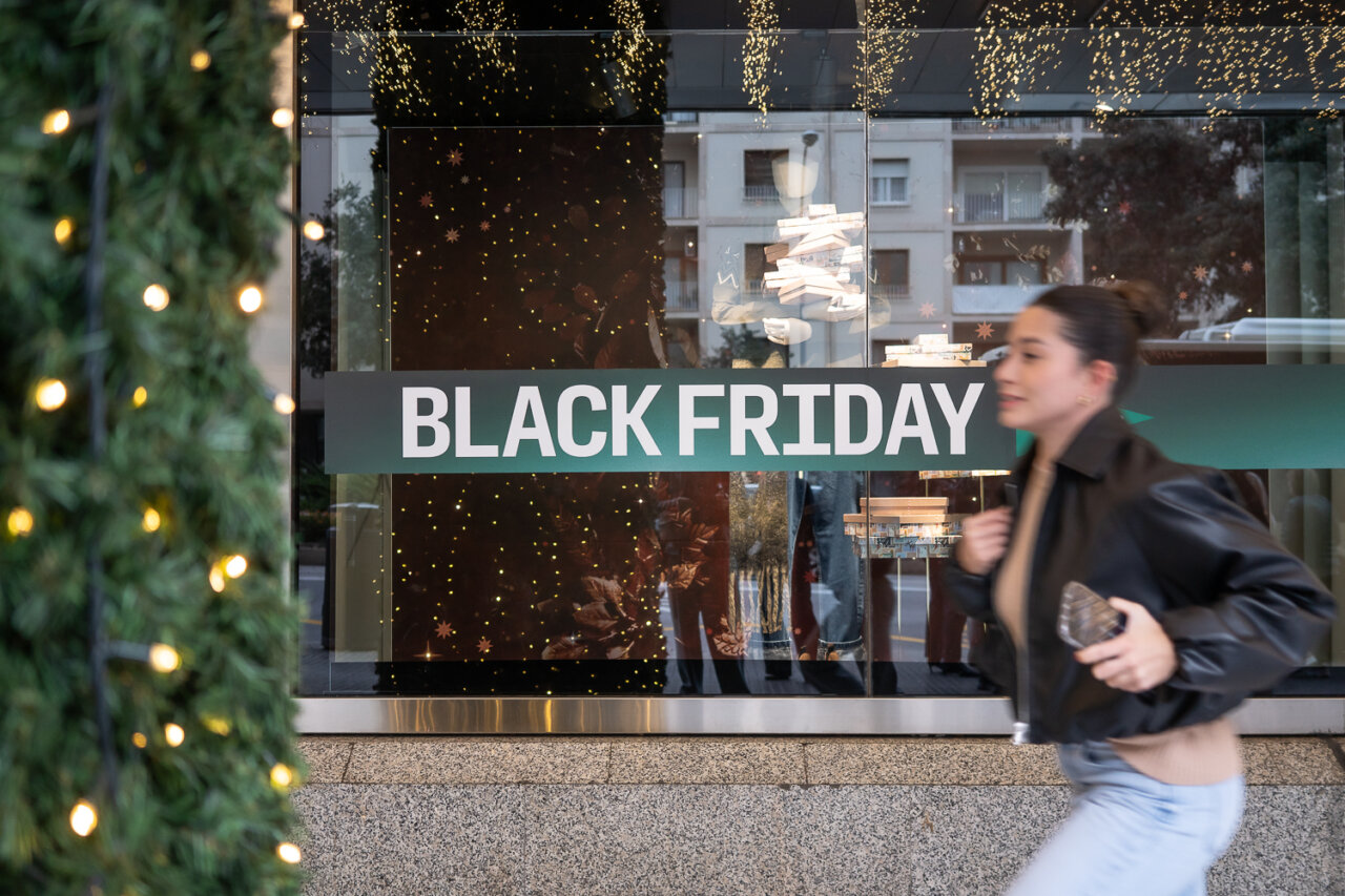 Mujer corriendo frente a una tienda con cartel de Black Friday