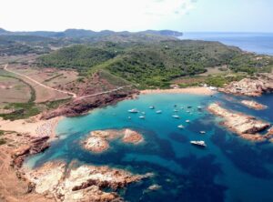 Vista aérea de Cala Pregonda en Menorca con barcos y paisaje natural