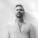 David Guetta posando con una camisa blanca en un fondo claro