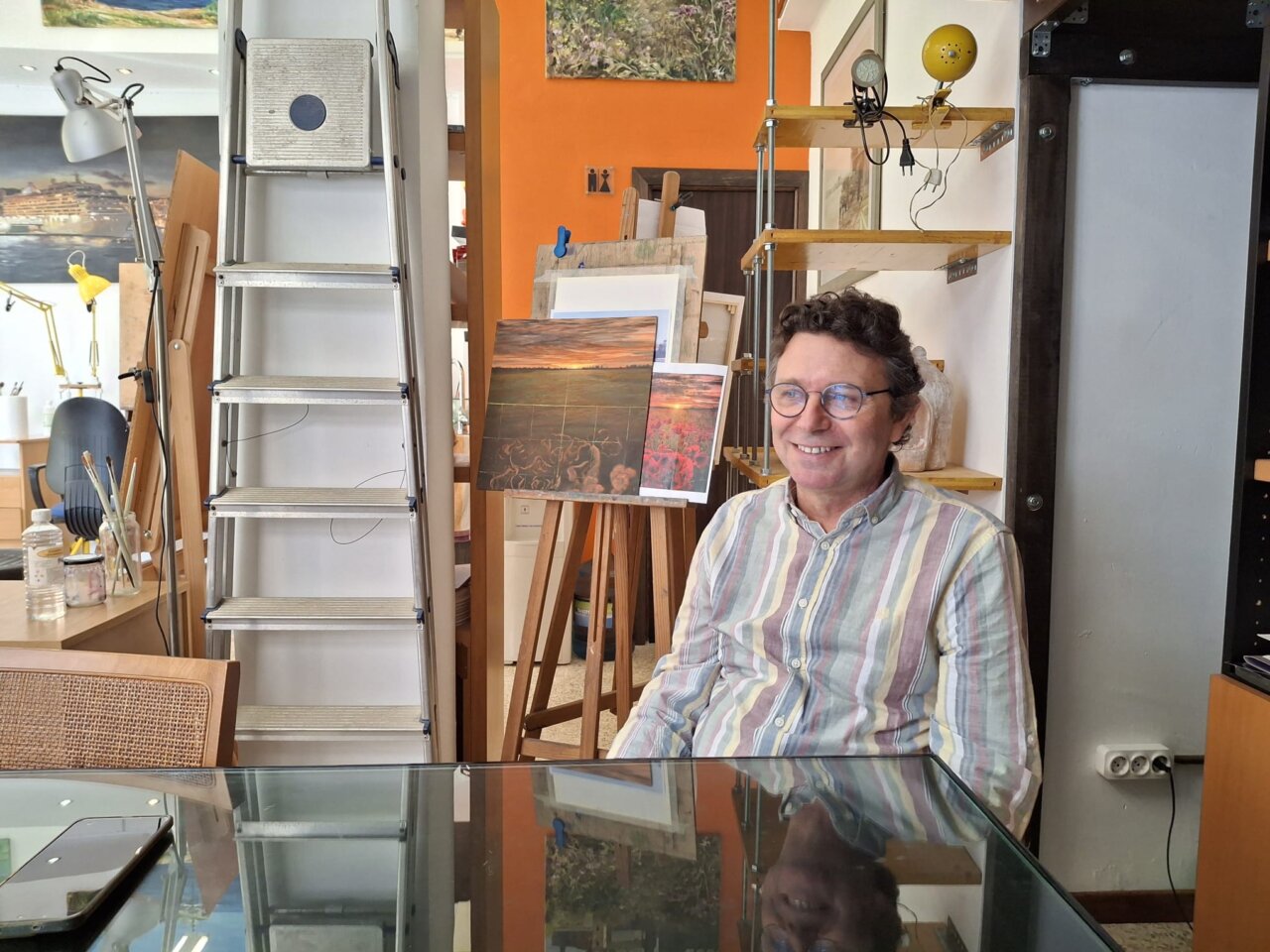 David Santos sonriendo en su estudio de pintura con obras de fondo