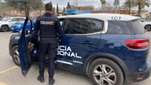 Agente de la Policía Nacional junto a un vehículo policial en un estacionamiento.