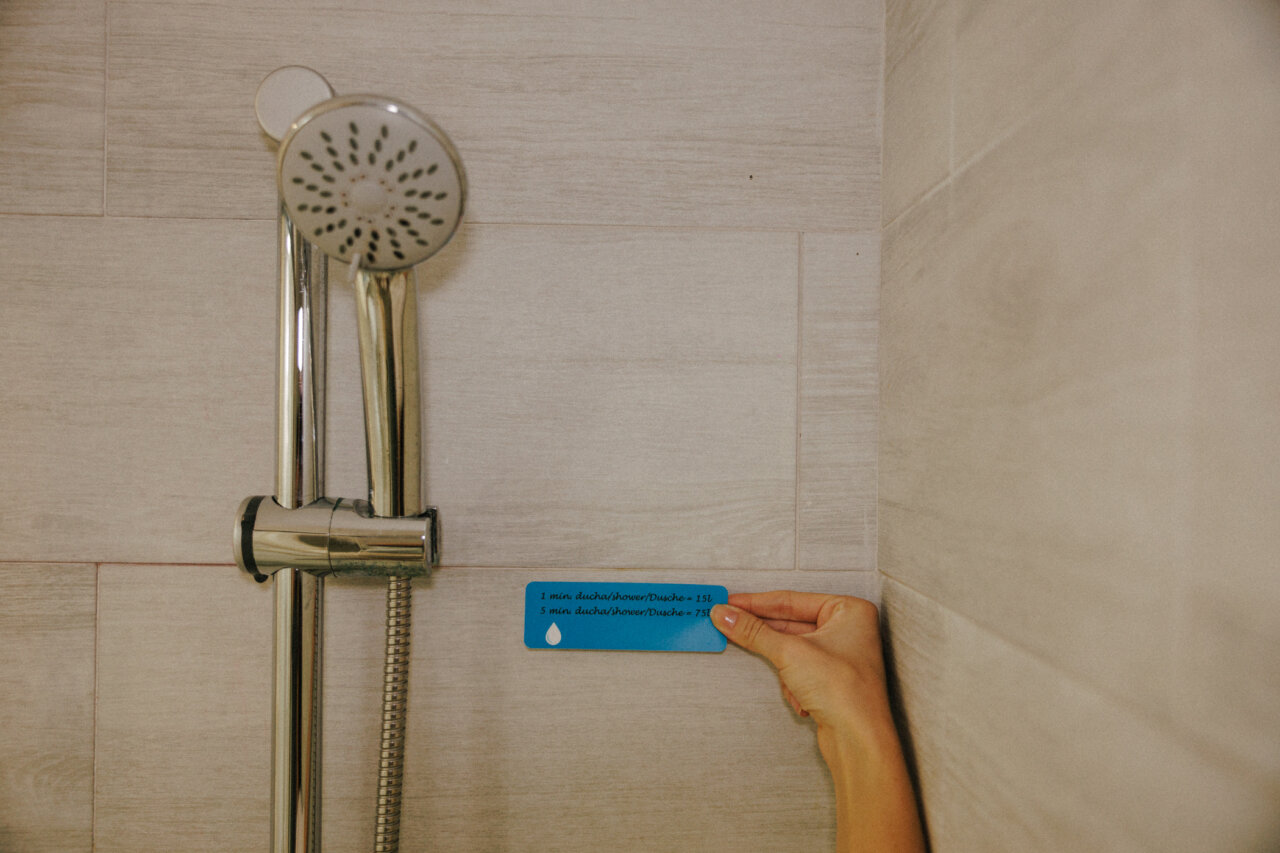 Persona sosteniendo una tarjeta sobre el consumo de agua en la ducha