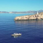 Vista del mar en Magaluf con un barco y una isla rocosa.